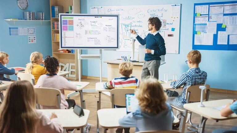 Elementary students and a teacher sitting together in a classroom, engaged in a group discussion.